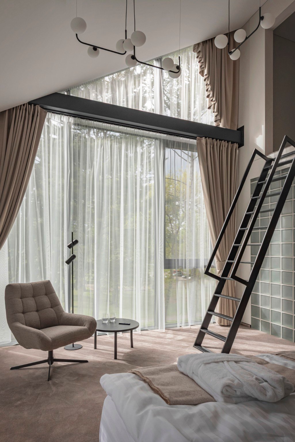 LAJOS hotel loft room with tall windows and forest light