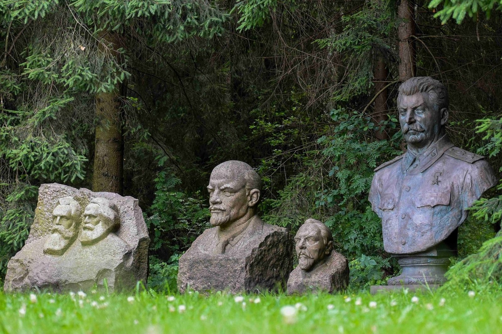 Soviet-era sculptures displayed among trees at Grūtas Park