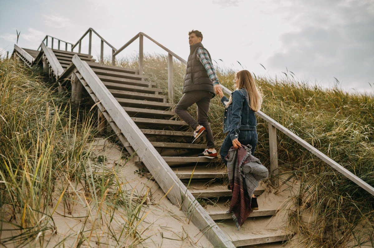 Visitors climbing wooden stairs through the dunes near Nida